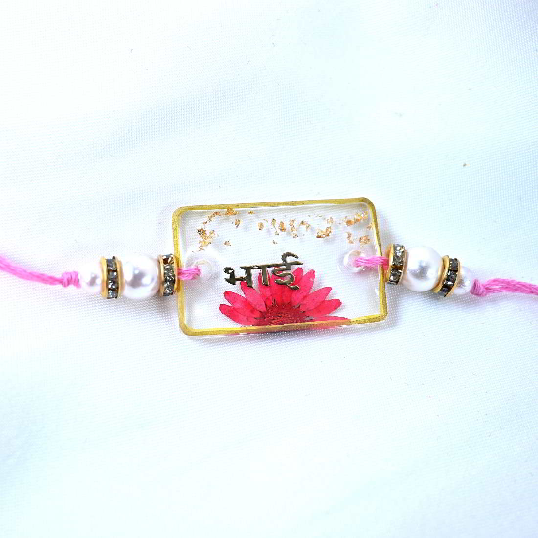 Beautiful Transparent Rakhi With Pink Flower Golden Text Bhai